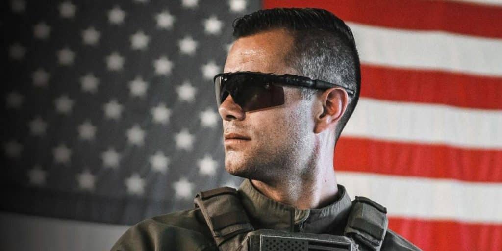 soldier wearing sunglasses in front of flag