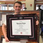student holding UGA frame in bookstore