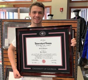 student holding UGA frame in bookstore