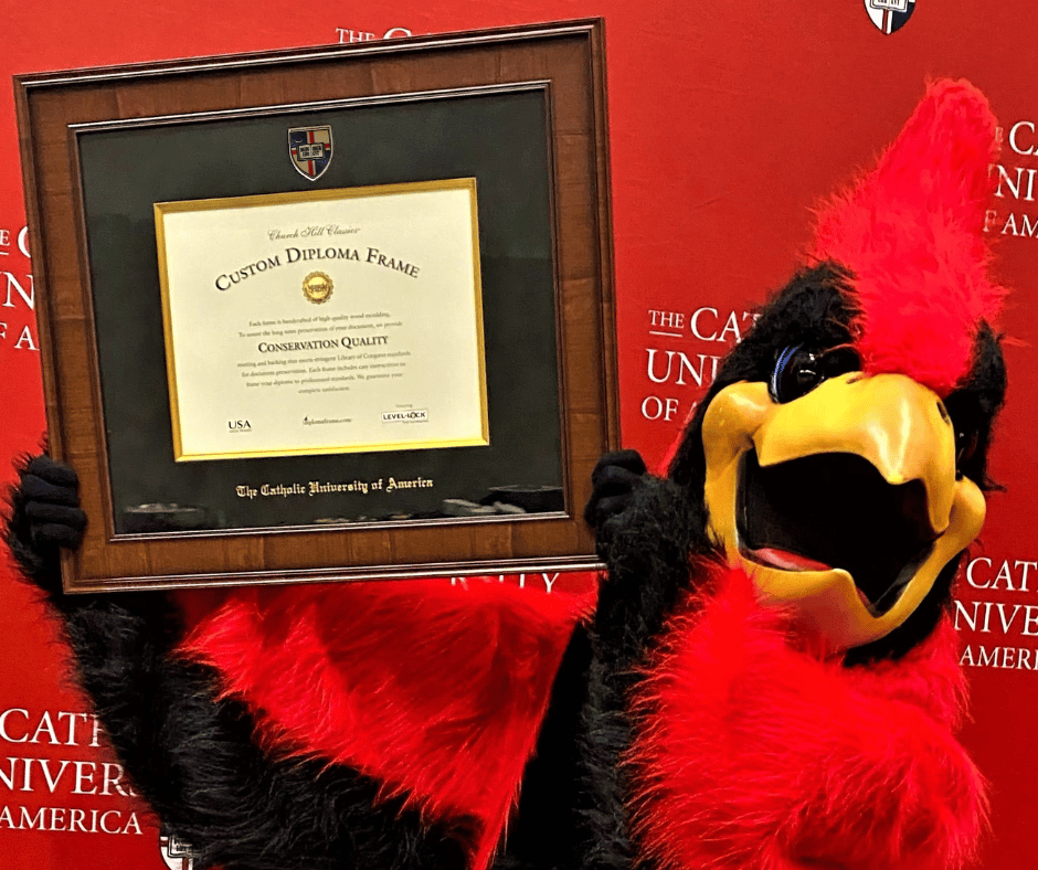 cardinal mascot holding catholic university diploma frame