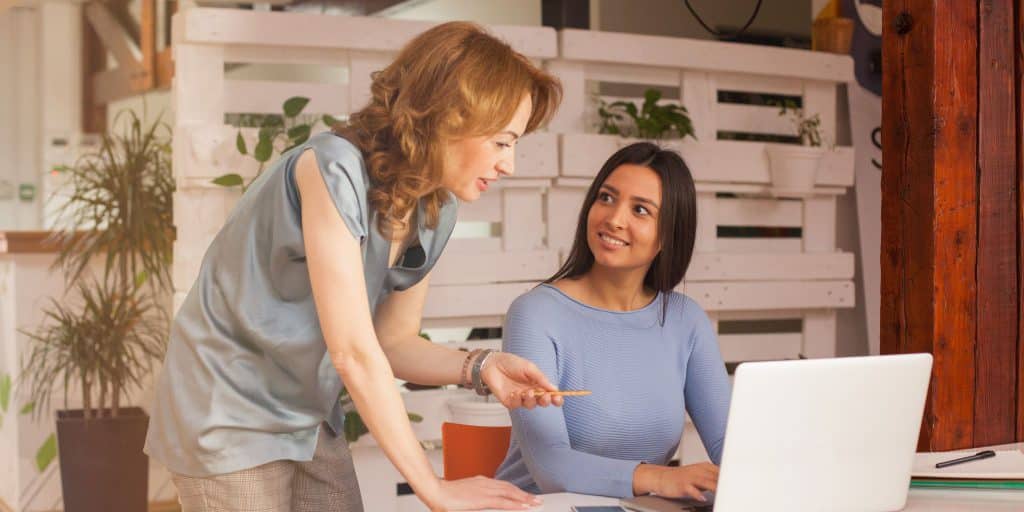 student at internship learning from boss at computer