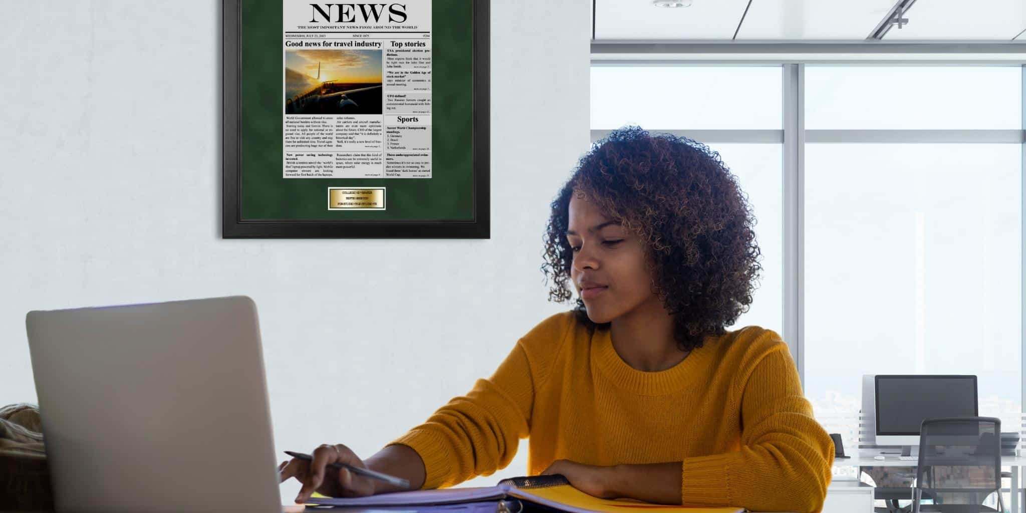 college student at laptop in newsroom