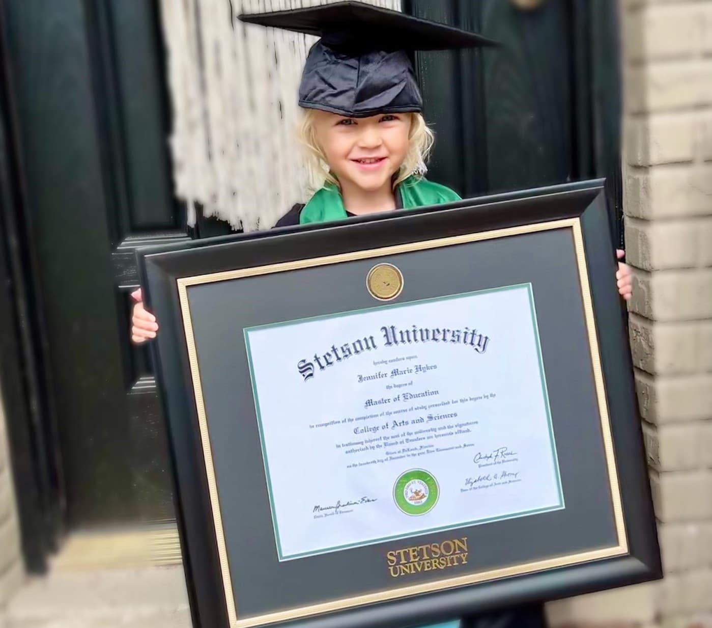 little girl in grad cap holding stetson university frame