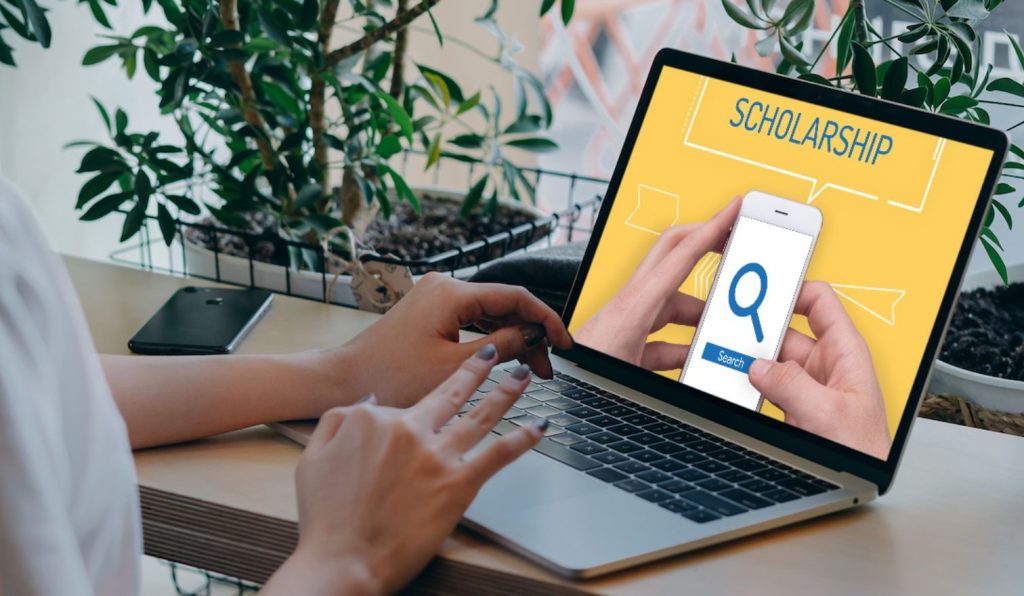 hands typing on laptop with scholarship search onscreen