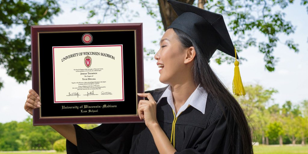 Graduate smiling looking at her UWM Law School degree frame