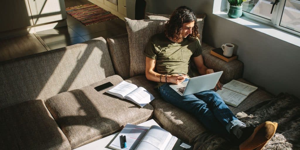 male student sitting on couch studying