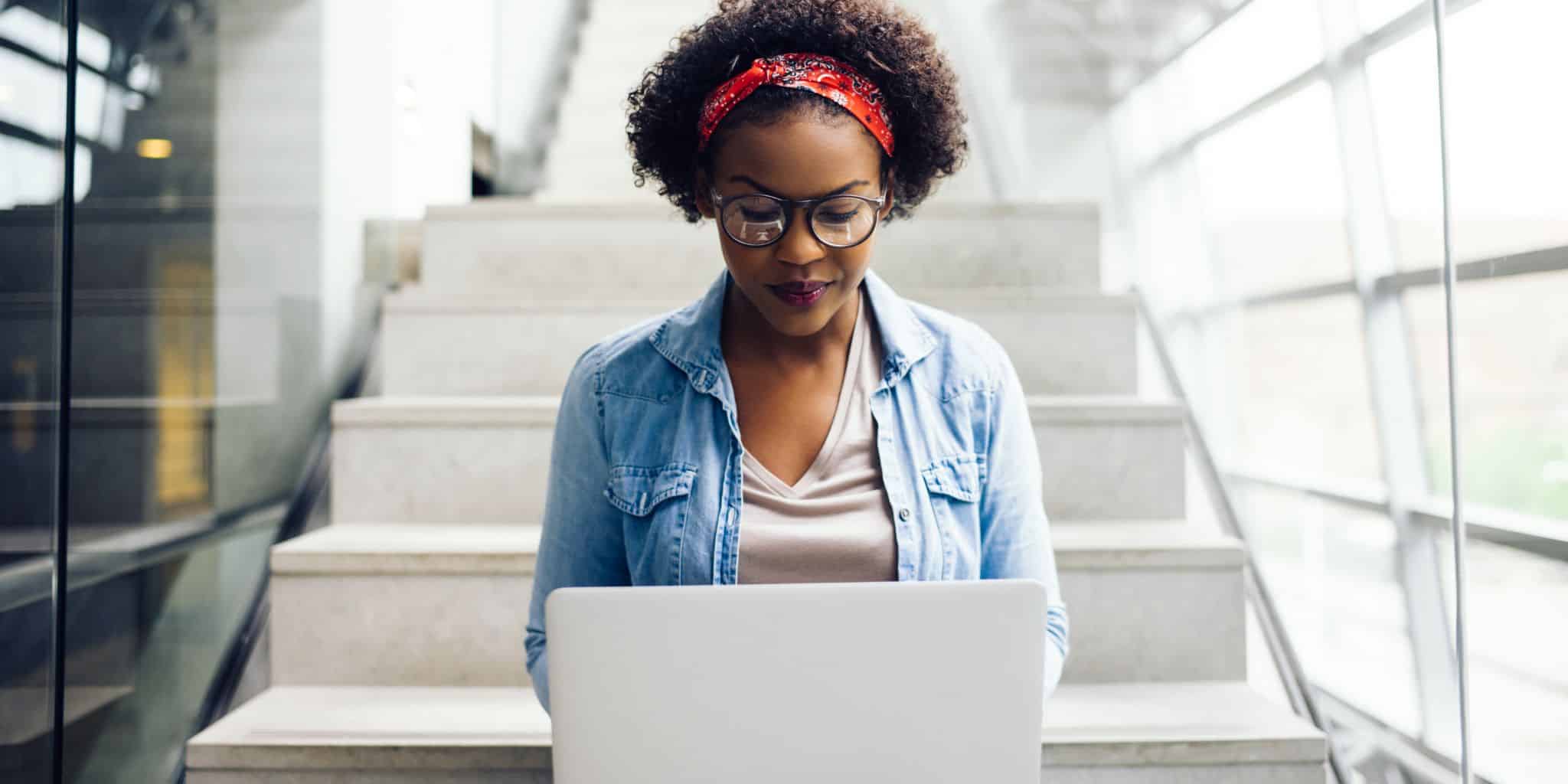 female student sitting on steps on laptop