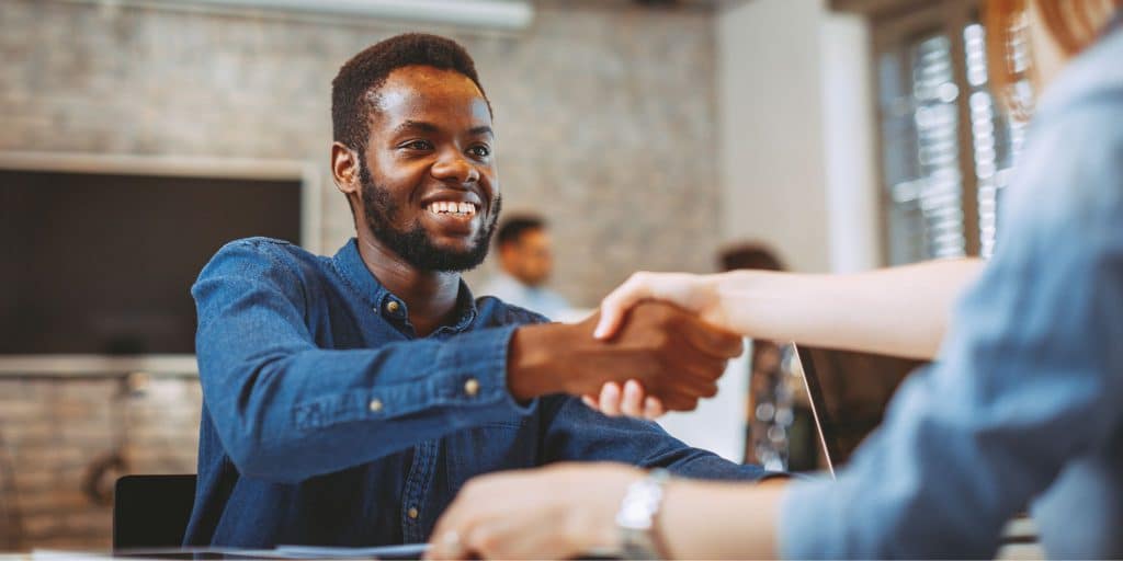 man in blue shirt shaking job interviewers hand