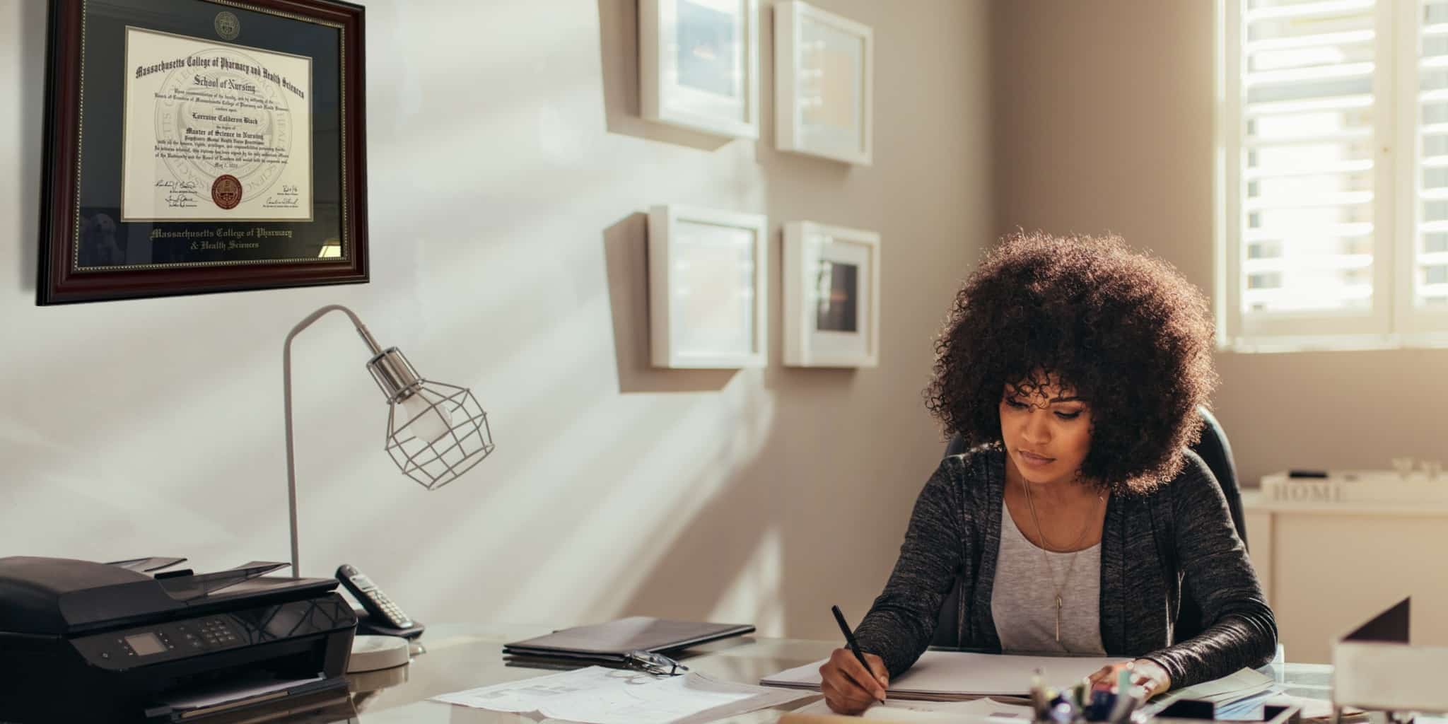 woman working at desk with framed diploma on wall