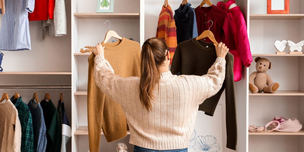 woman in a closet looking at different sweater options