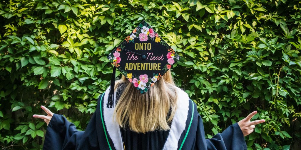 grad facing backward with decorated 'on to the next adventure' grad cap with flowers