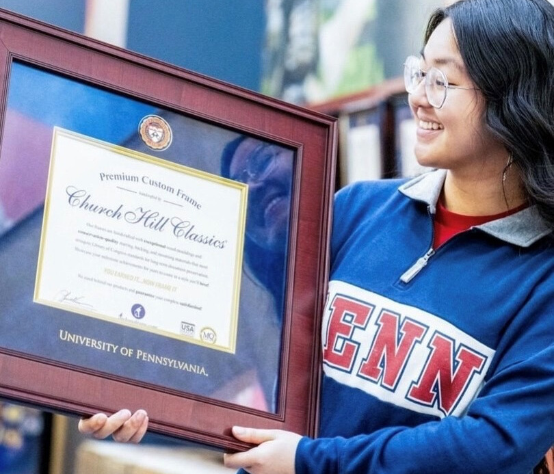 UPenn graduate smiling and holding up Church Hill Classics diploma frame