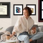 woman on couch with VCU diplom frame and Duke University degree frames behind him