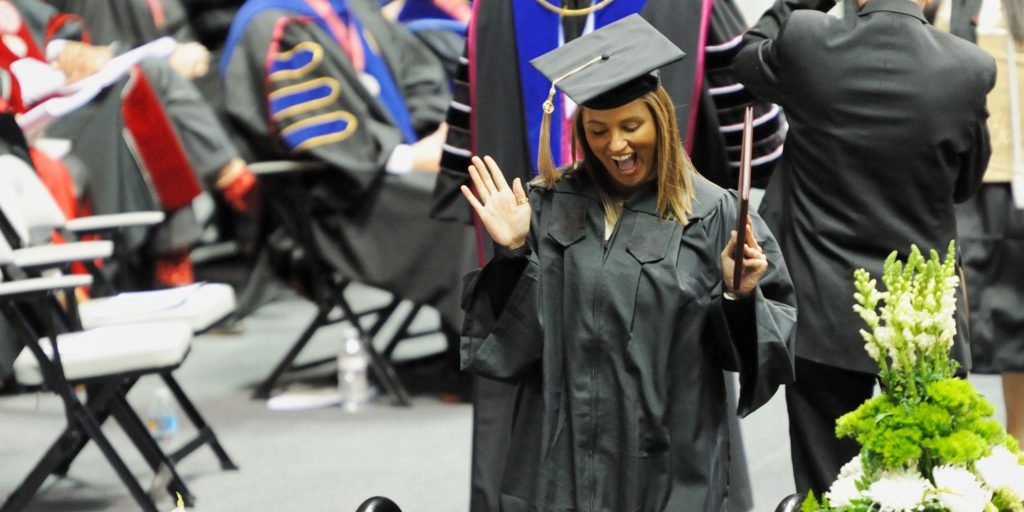 smiling graduate walking across stage with diploma