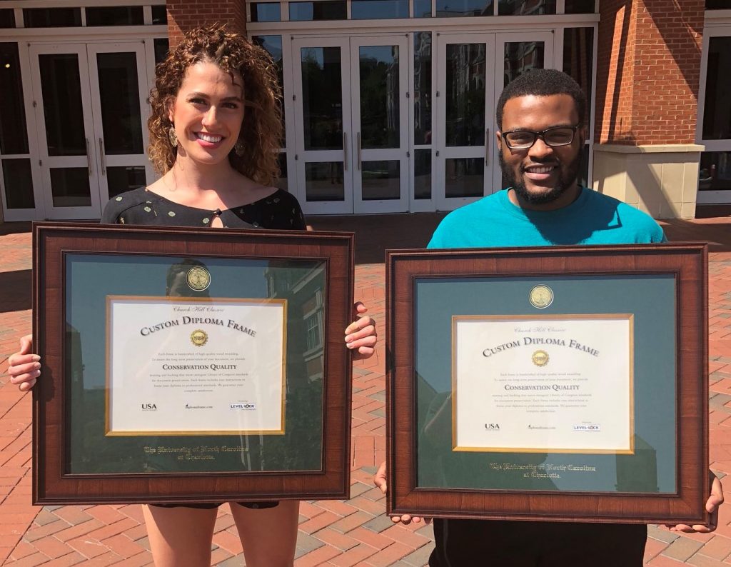 boy and girl standing outside holding custom diploma frames