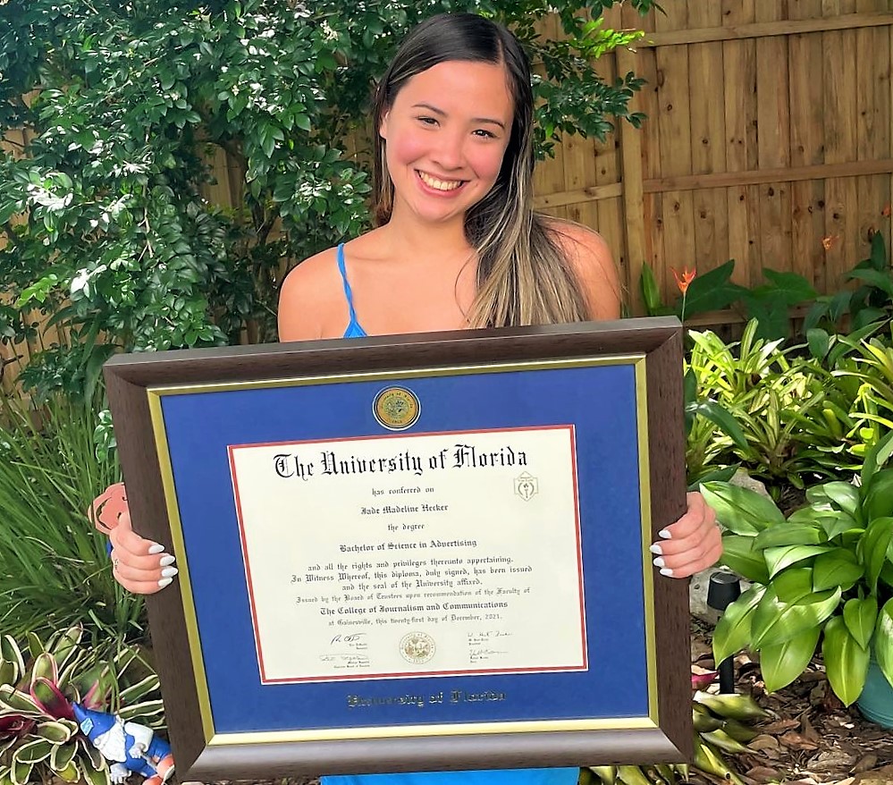 smiling woman holding blue UF diploma frame