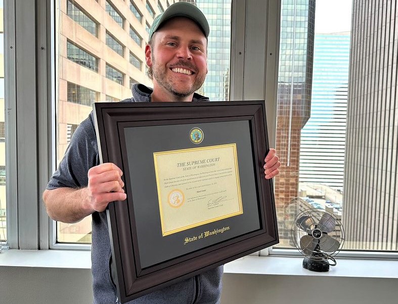 smiling man holding state of Washington state bar license frame