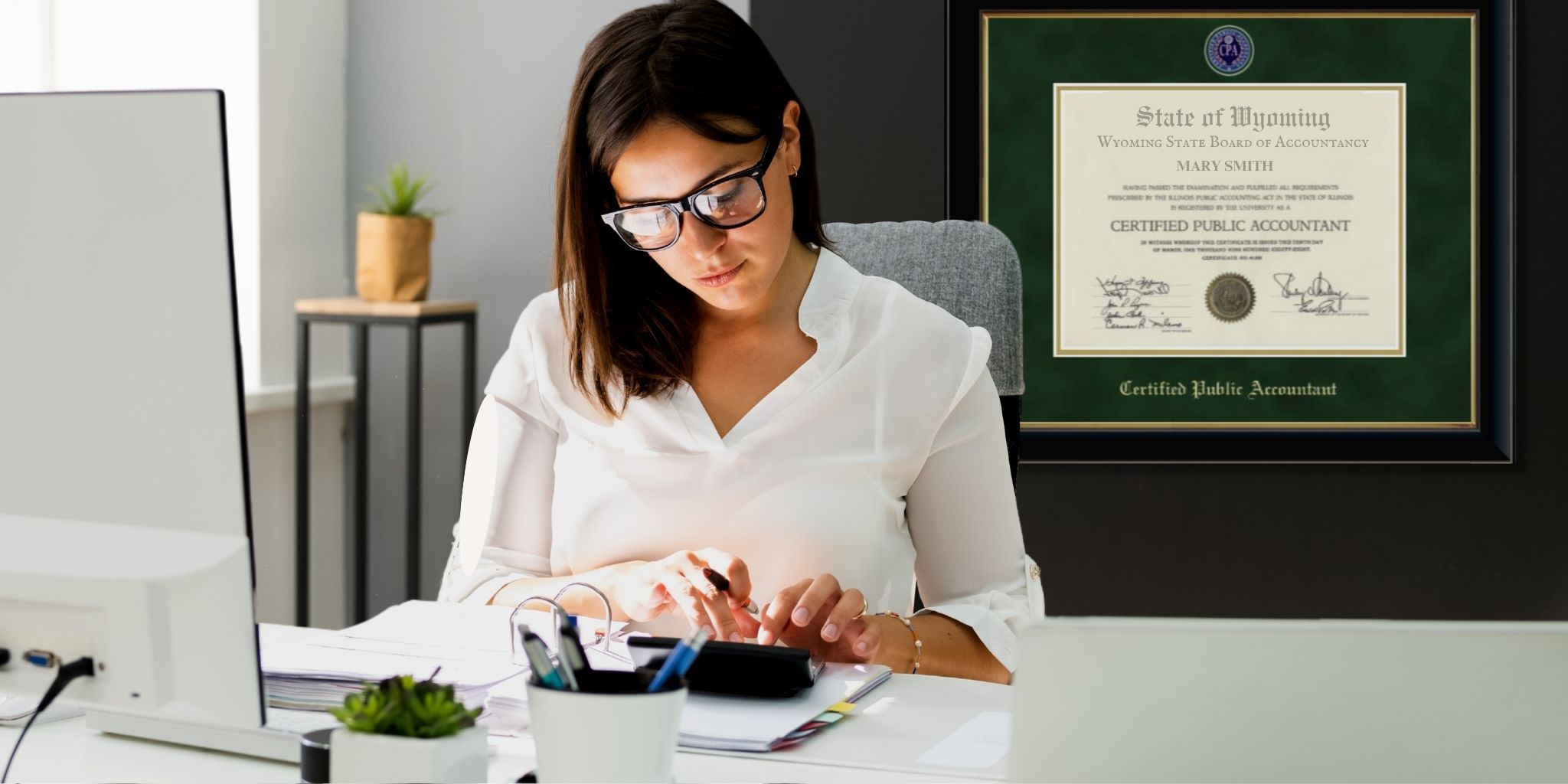 Accountant at desk with CPA license frame on wall