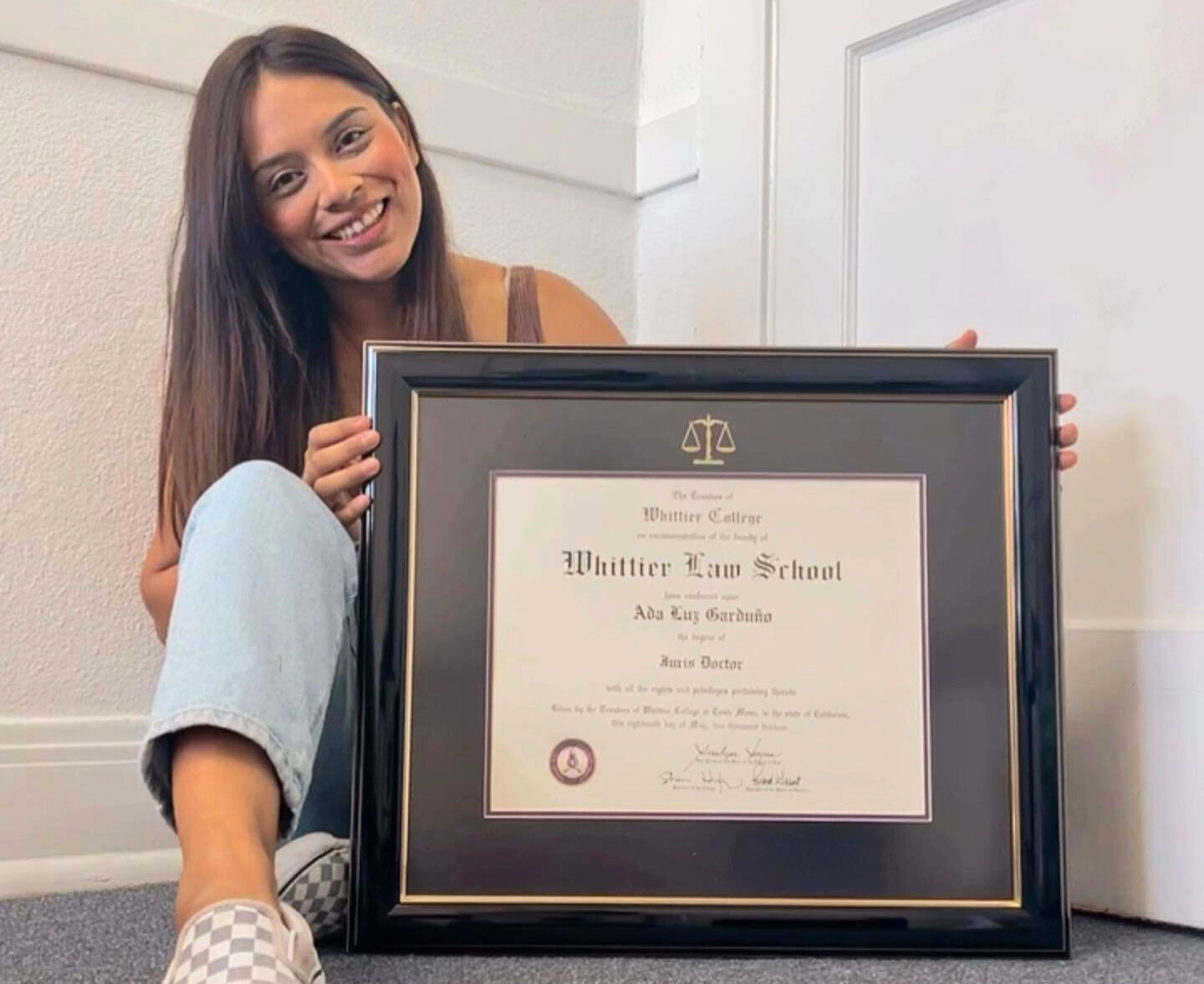 whittier law school graduate sitting next to custom frame on floor