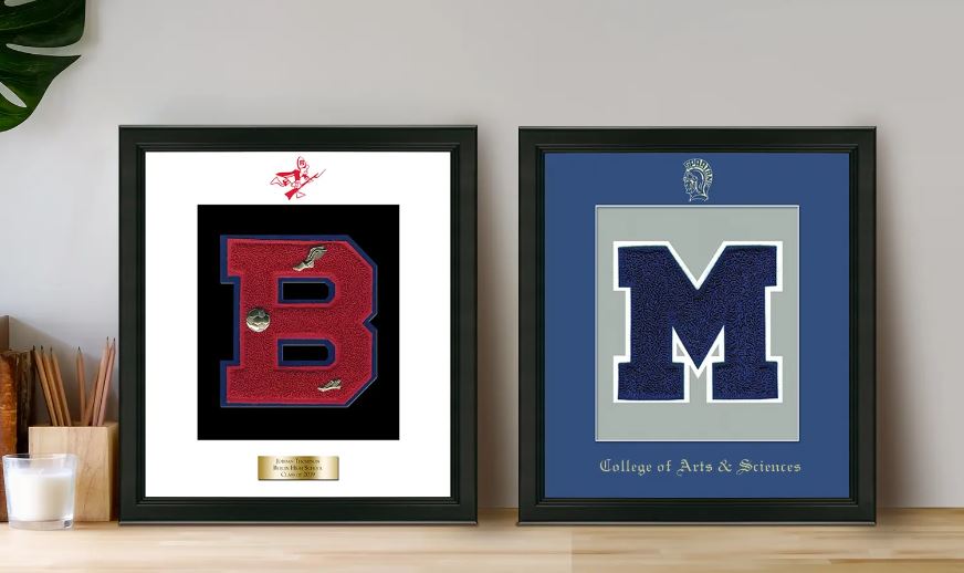 two varsity letter frames side by side on a desk next to a pencil holder