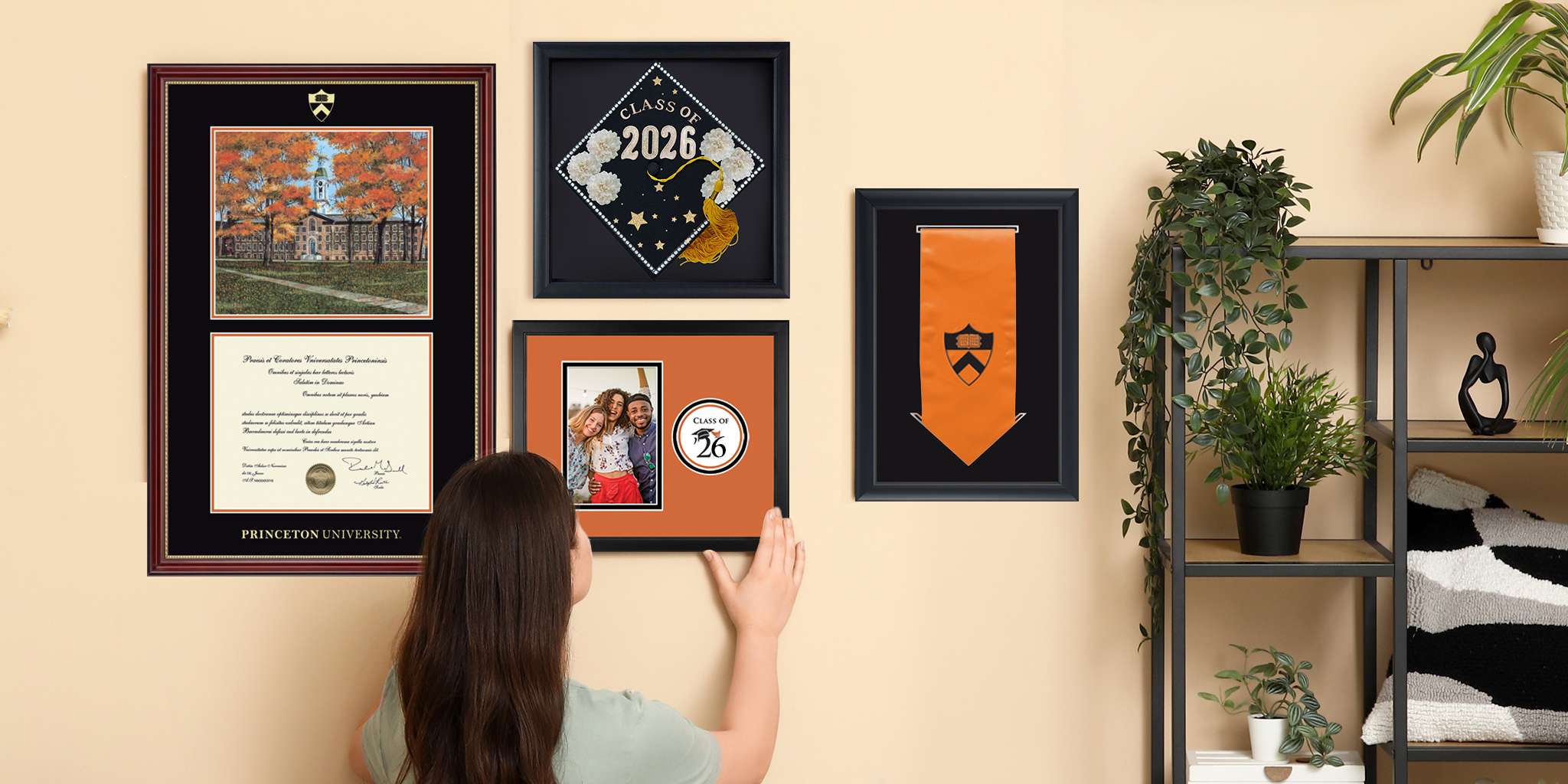 college student hanging custom photo frame on gallery wall featuring grad cap shadow box frame, graduation stole frame, and Princeton University campus scene diploma frame