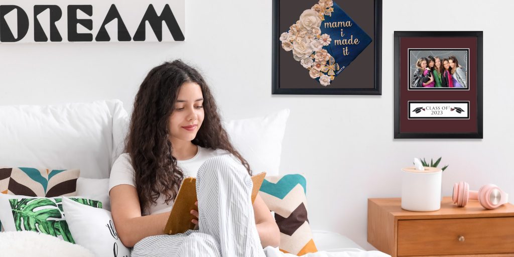 girl high school student sitting on bed with grad cap frame and custom photo frame on wall