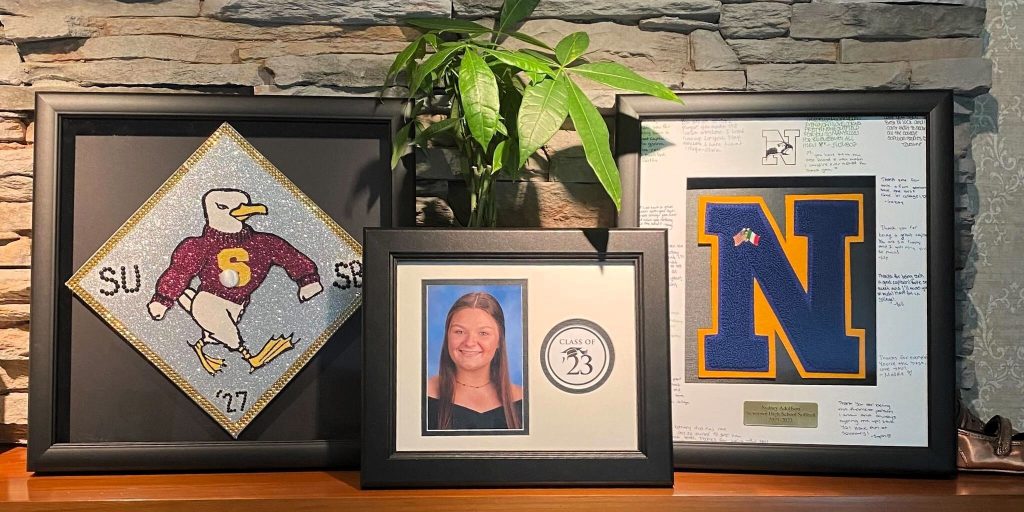 mantle with decorated grad cap in frame, custom photo frame, and varsity letter frame next to plant