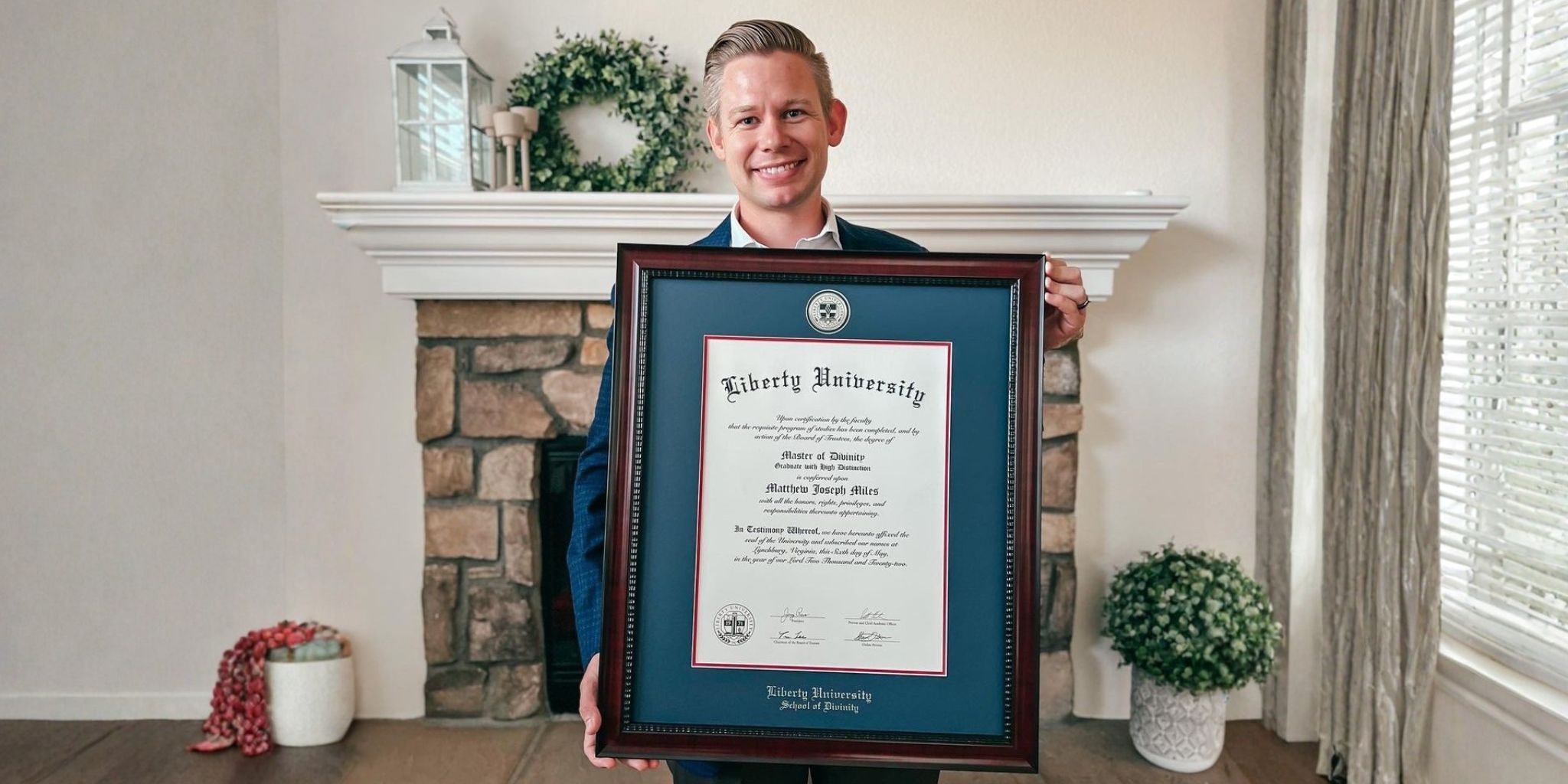 Smiling Liberty University graduate holding handcrafted luxury Liberty diploma frame