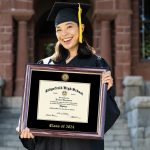 Smiling high school valedictorian holding class of 2024 diploma frame