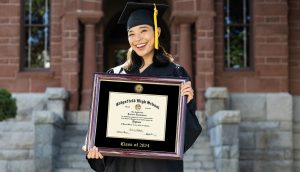 Smiling high school valedictorian holding class of 2024 diploma frame