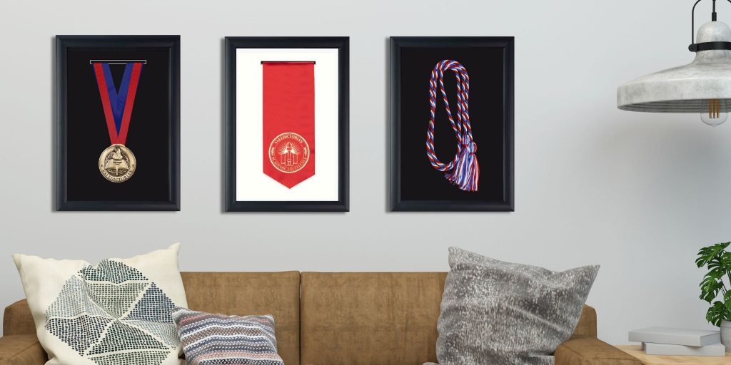 Framed valedictorial medal sash and cords on wall above couch