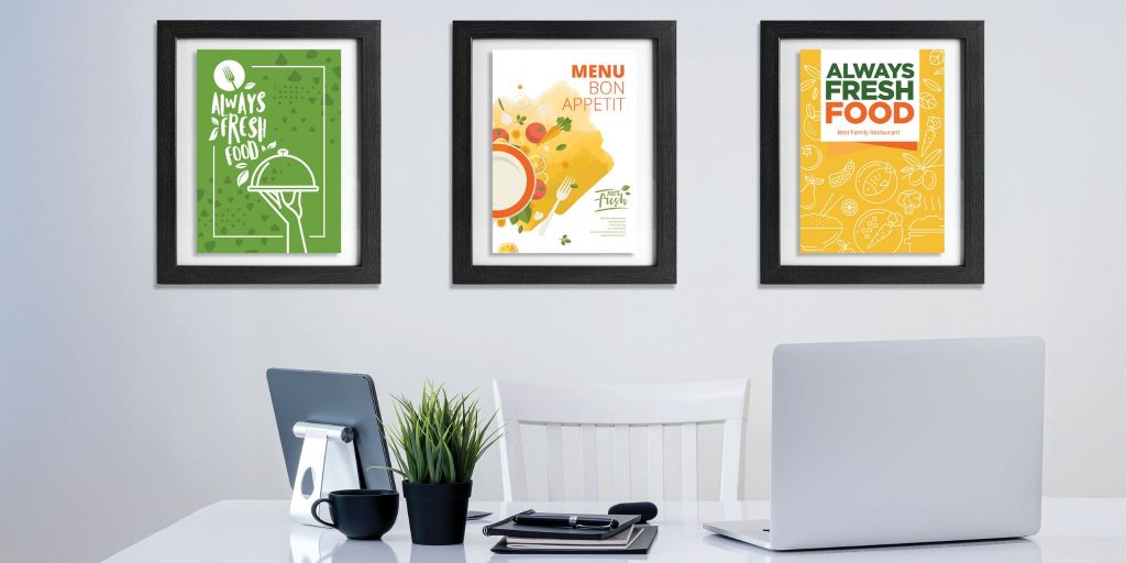 three black frames on wall with float mounted magazine covers in office behind desk