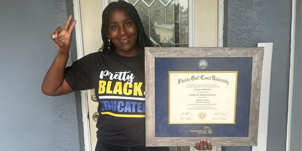 woman smiling and giving peace sign while holding her Florida Gulf Coast University diploma frame