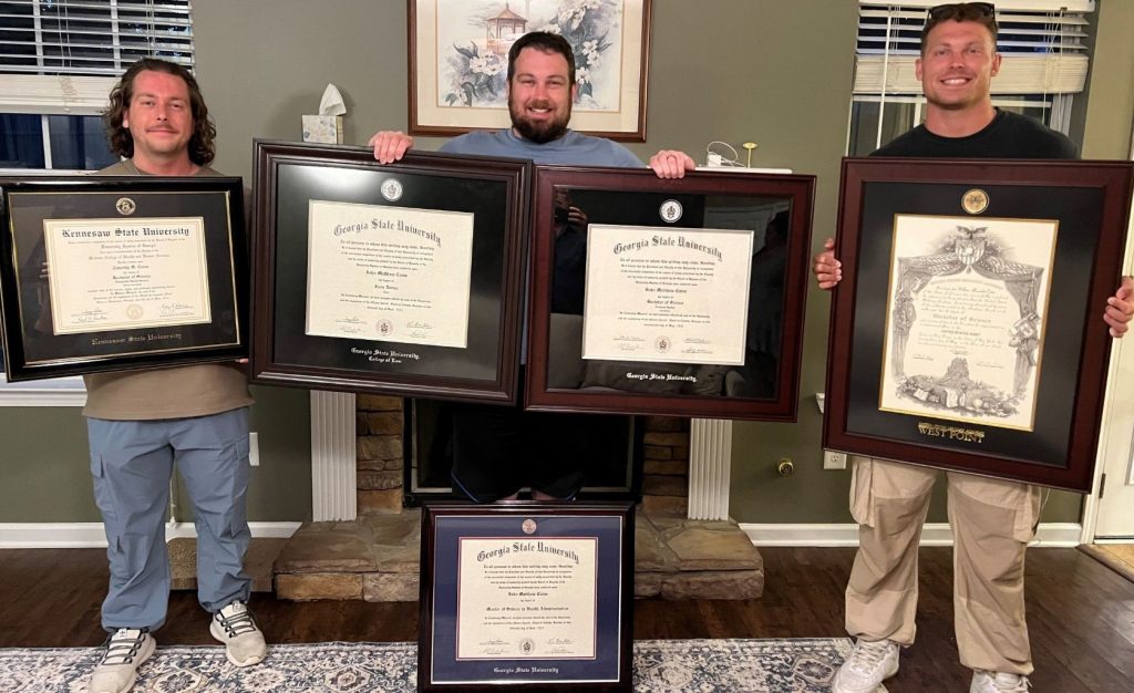 three brothers holding their five diploma frames