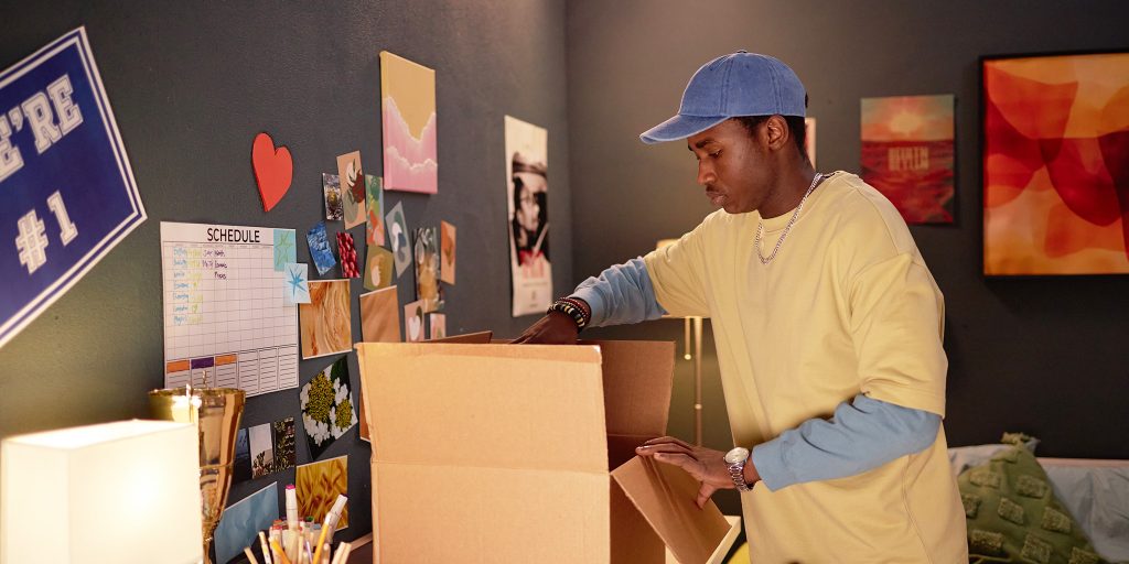 college student unpacking a box in new dorm room