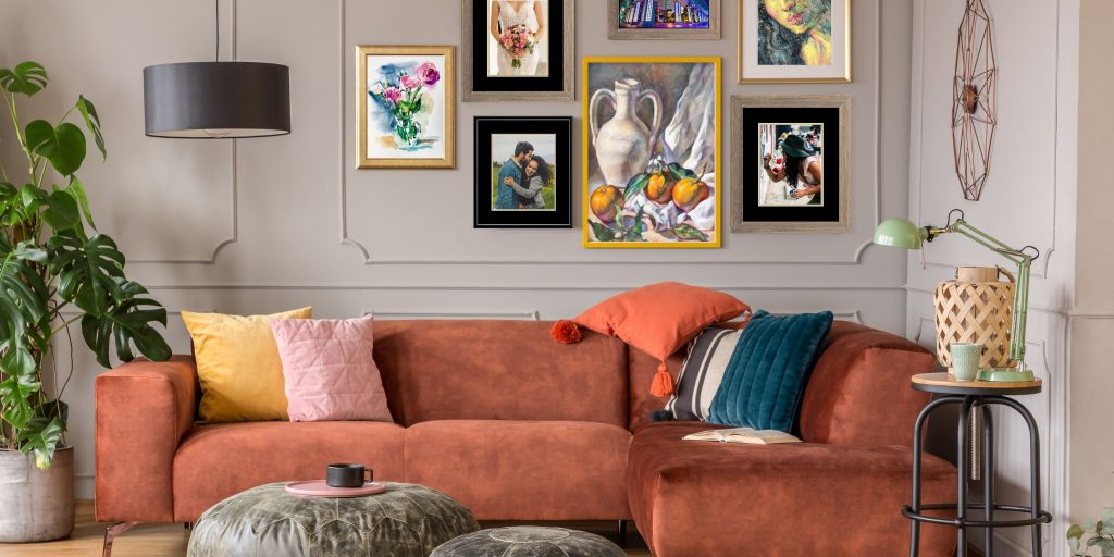 mix of colorful framed art and photo frames over russet brown couch