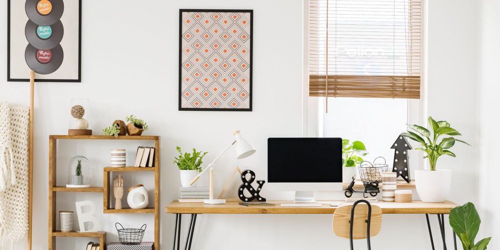 cozy dorm room with desk, computer, and plants with posters on walls