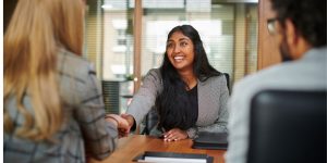 smiling woman shaking interviewer's hand in office