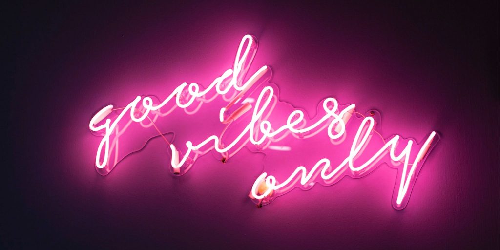 neon pink light up sign that says 'good vibes only' on dark background