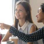 woman pointing to laptop as she sits next to student