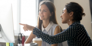 woman pointing to laptop as she sits next to student