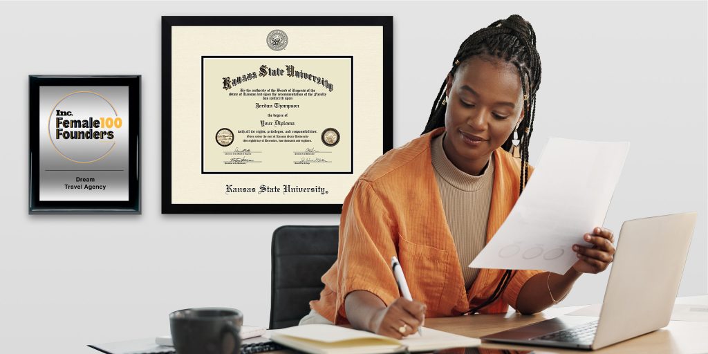 woman working at a desk with custom plaque and diploma frame on wall behind her