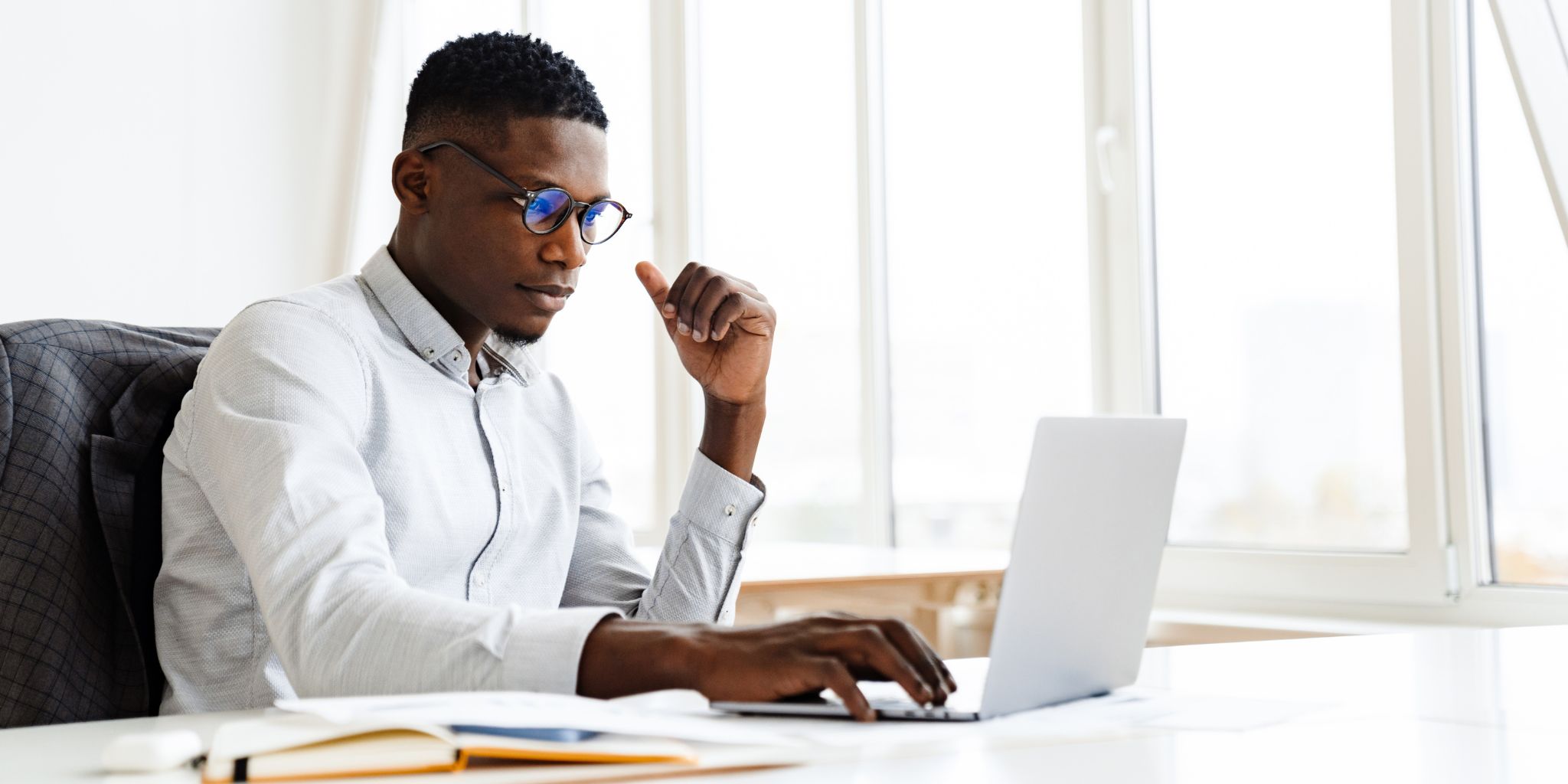 student in brightly lit room working at desk on laptop