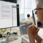 Side profile of person with glasses looking at AI chat on laptop.