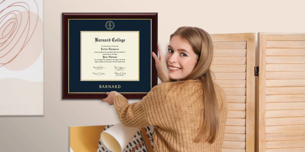 smiling woman hanging a Barnard College diploma frame on the wall