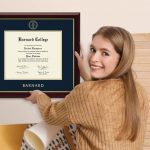 smiling woman hanging a Barnard College diploma frame on the wall