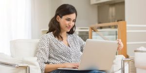 woman sitting in white leather chair looking at laptop on her lap