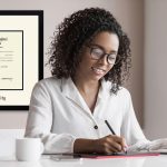 Woman working at an office desk with custom Howard University frame on the wall behind her