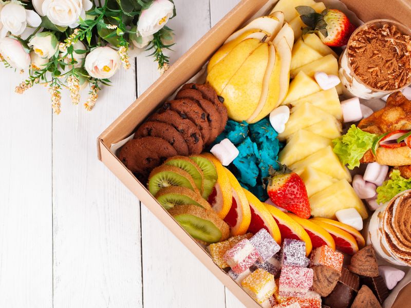 a graduation gift box filled with gourmet food next to flowers
