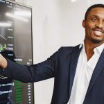 Man in suit holding pointer against screen showing business marketing chart.